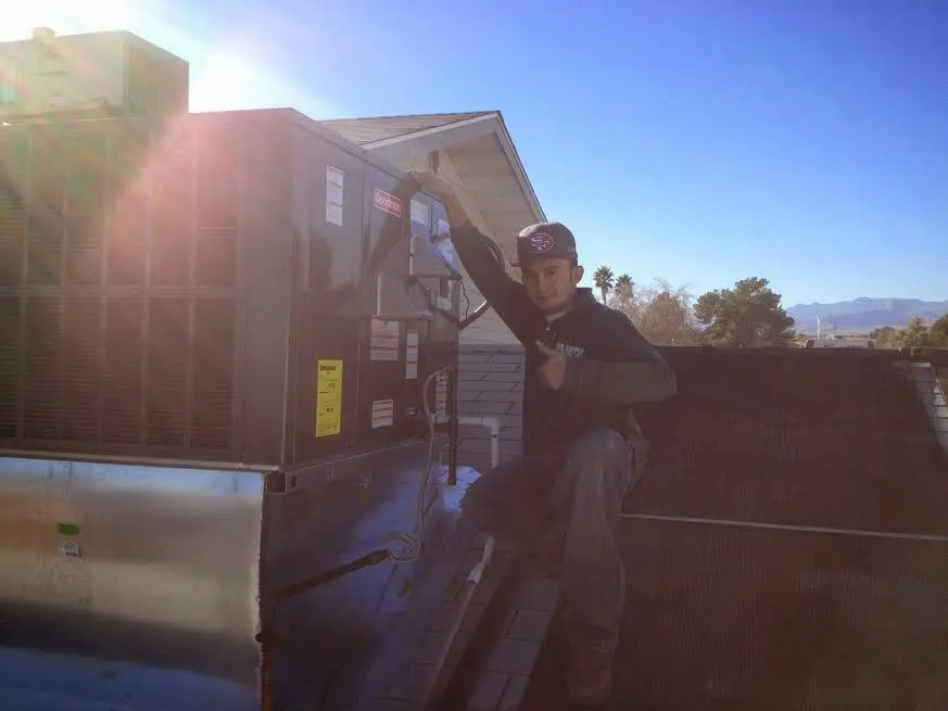 HVAC technician performing AC Tune-Up on a rooftop unit in East Point